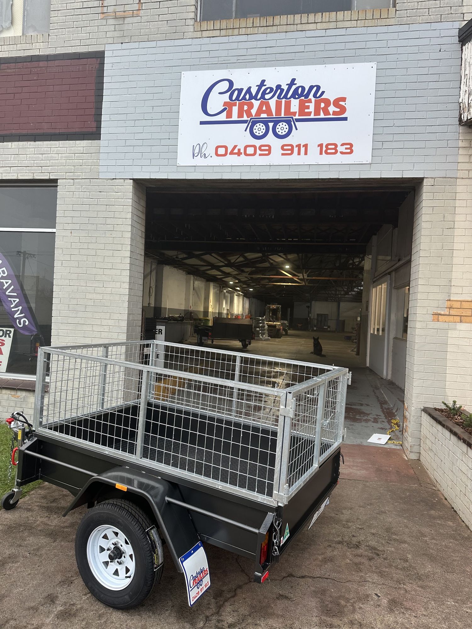 New single axle cage trailer outside the Casterton Trailers workshop, under the shop sign